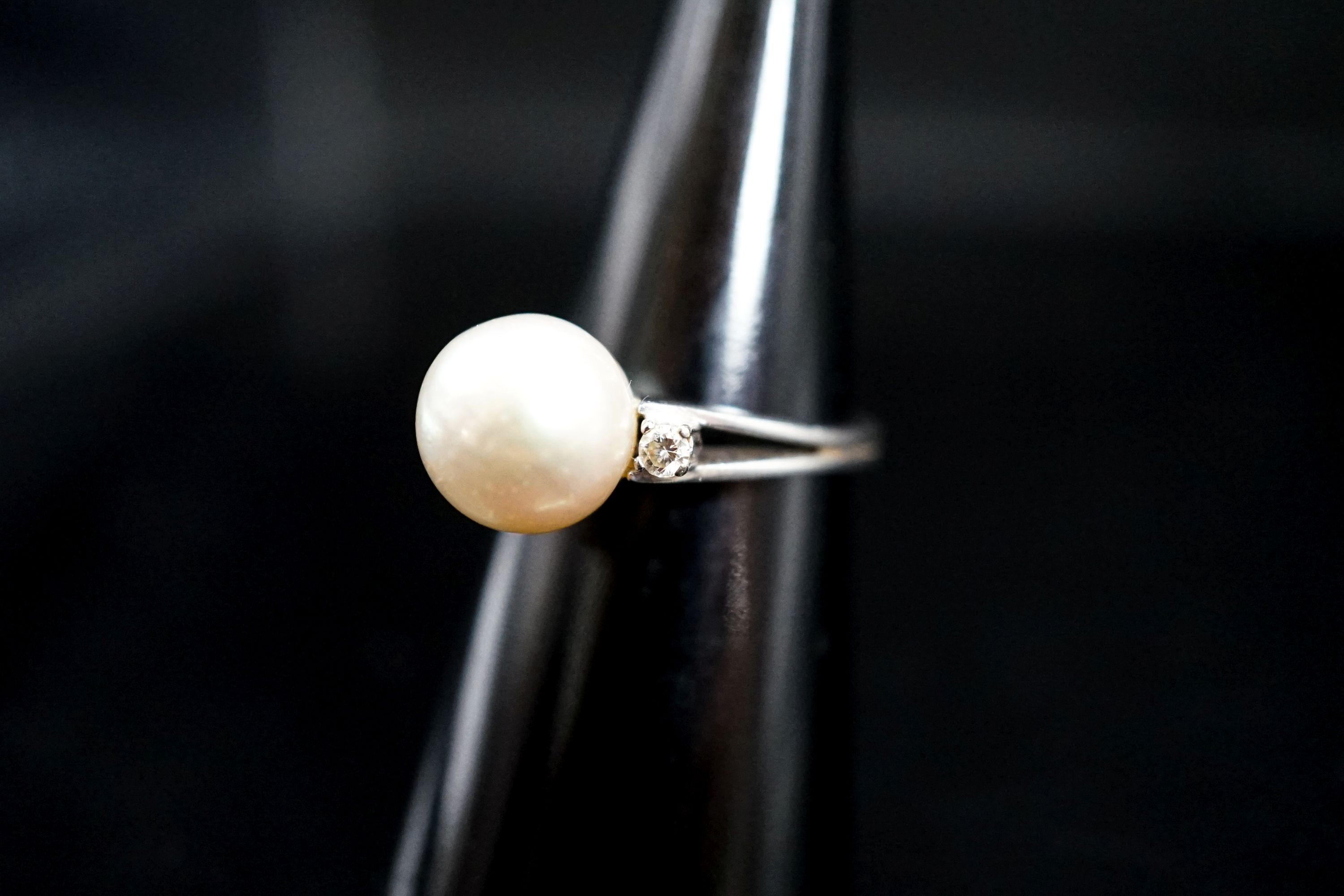 A white metal and single stone cultured pearl dress ring, with diamond set shoulders, size L/M, gross 4.1 grams.